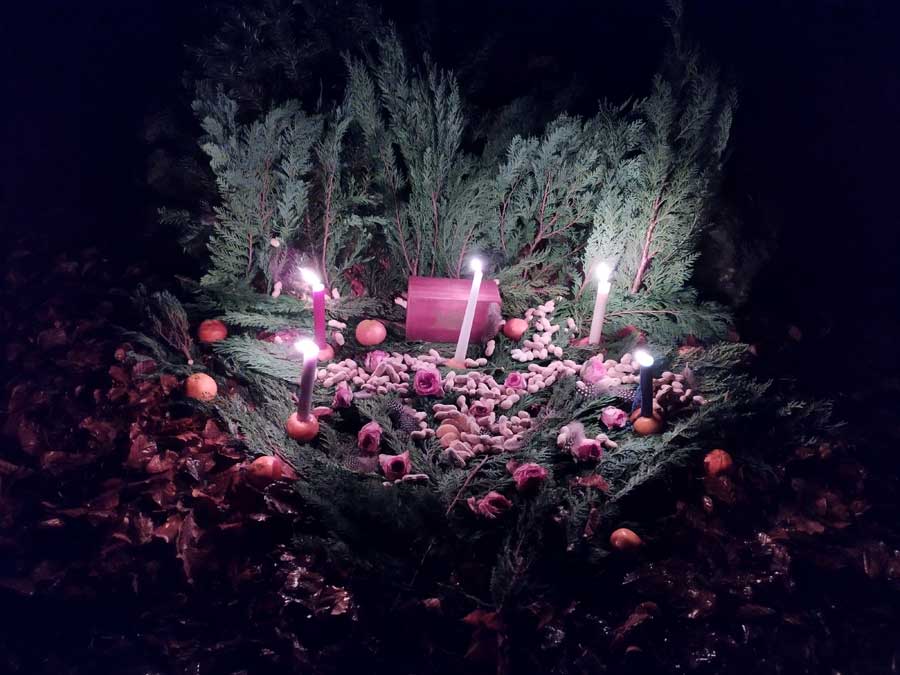 Altar mit Kerzen, Tannenästen und Erdnüssen.