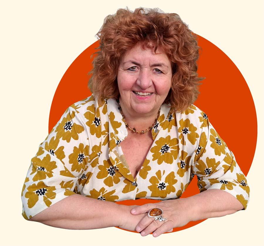 Pamela Anna Guggenheim stützt sich auf einen Fels und lächelt in die Kamera.