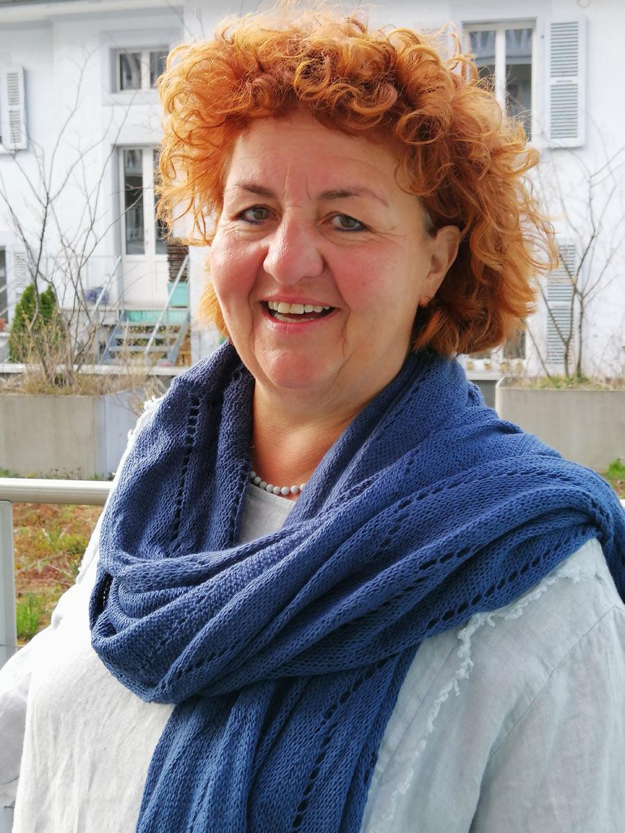Pamela Anna Guggenheim stützt sich auf einen Fels und lächelt in die Kamera.
