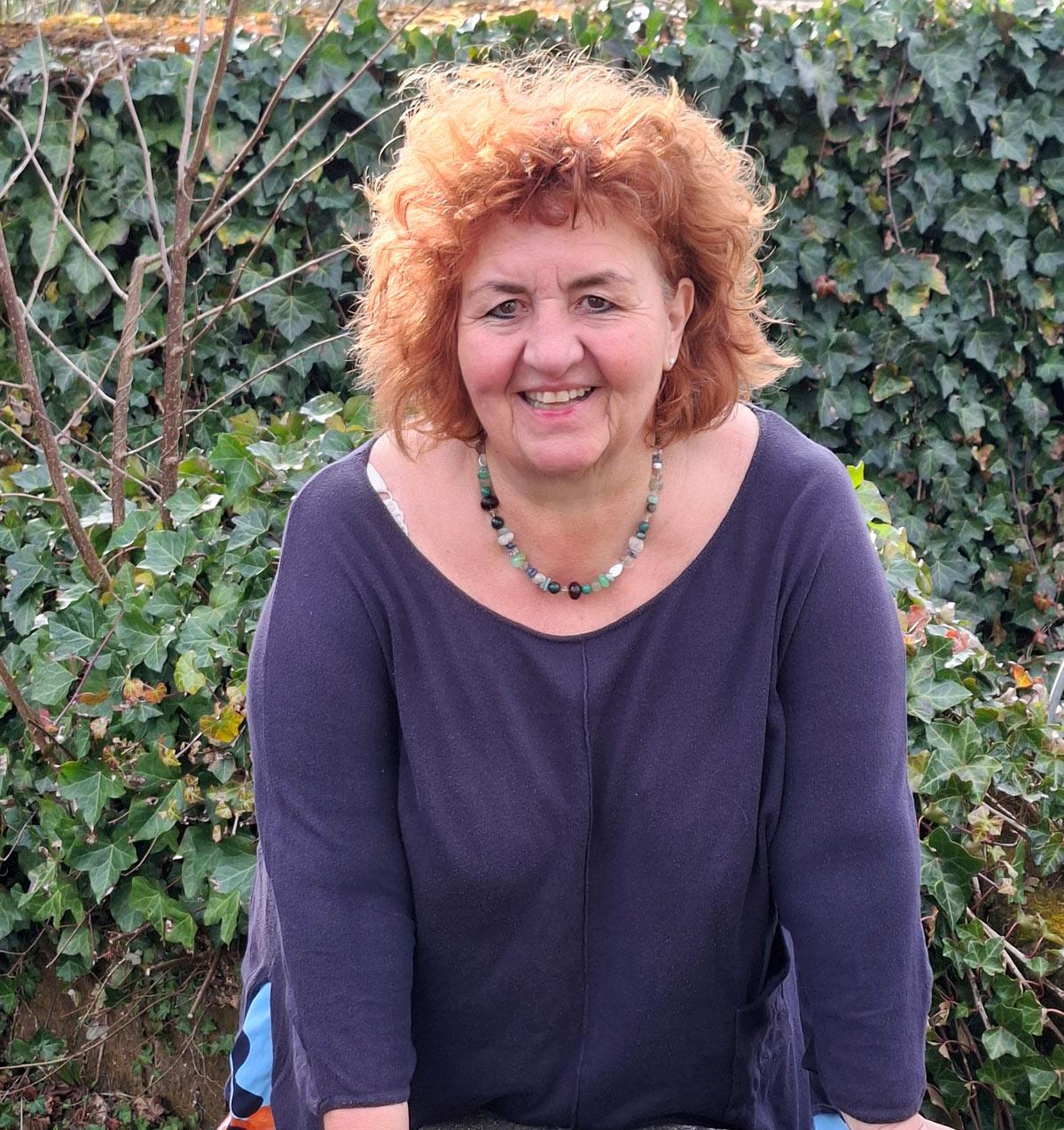 Pamela Guggenheim stützt sich auf eine Mauer und lächelt.