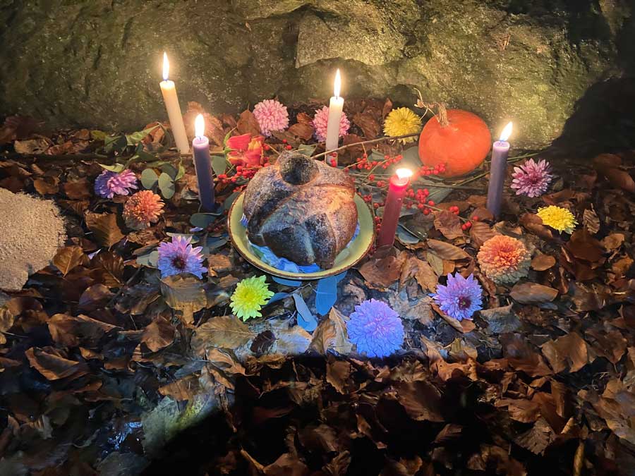Altar aus Blumen, Kerzen und einem Stein in der Mitte.
